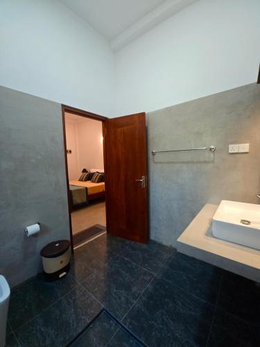 a bathroom with a sink and a door to a bedroom at Olee Villa in Bentota