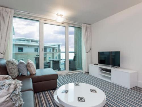 a living room with a couch and a large window at Reflections - Balcony Views of Poole Harbour in Poole