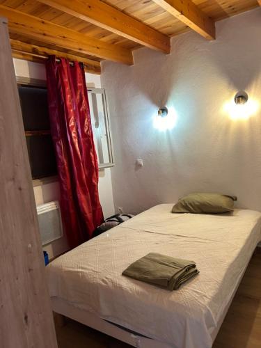 un lit dans une chambre avec un rideau rouge dans l'établissement Au cabanon, à Port-Saint-Louis-du-Rhône