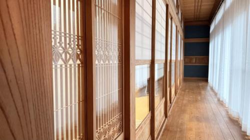 an empty hallway with glass doors and wooden floors at Irest Village Narita in Narita