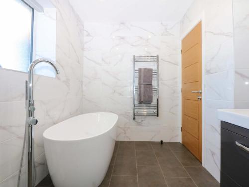 a bathroom with a white tub and a sink at Golygfa in Bodorgan