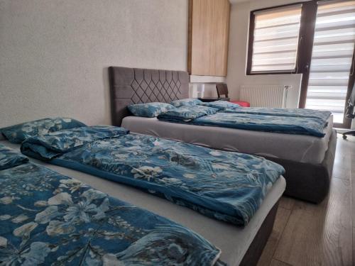 a bedroom with three beds with blue comforters at Apartman Gradina in Doboj