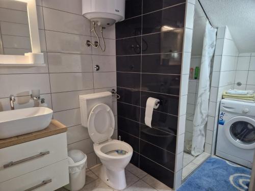 a bathroom with a toilet and a sink and a washing machine at Apartman Gradina in Doboj