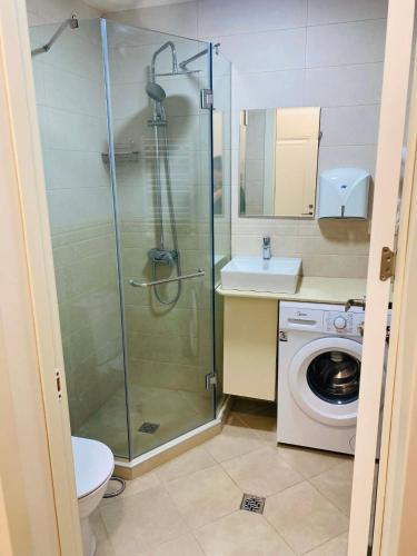 a bathroom with a shower and a washing machine at Holidays inkutaisi in Tsqnetʼi