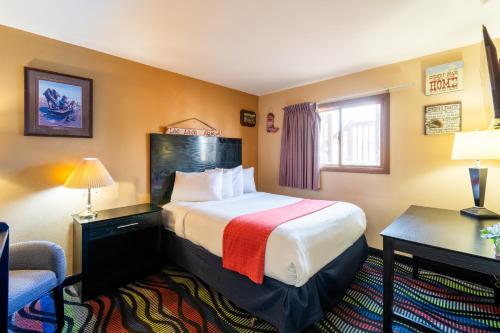 a hotel room with a bed and a desk and a chair at Sunset Motel and RV in Alliance