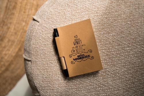 a book sitting on the side of a pillow at Noordzee, Hotel & Spa in Cadzand-Bad