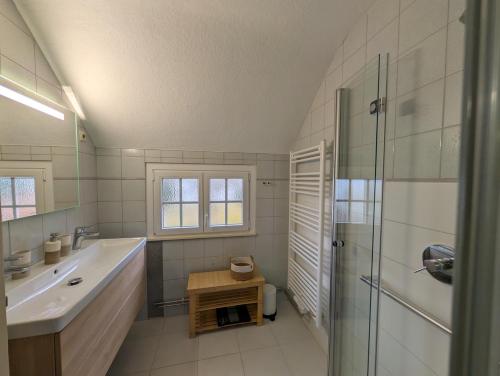 a white bathroom with a sink and a shower at Dreimädelshaus in Uhldingen-Mühlhofen