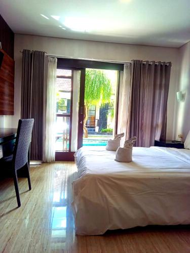 a bedroom with a large bed and a large window at NEW KUBU DI BUKIT apartemen & motor bike rental in Jimbaran