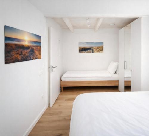 a white bedroom with a bed and a window at Gulfhof Wangermeer 1 Lotta in Hohenkirchen