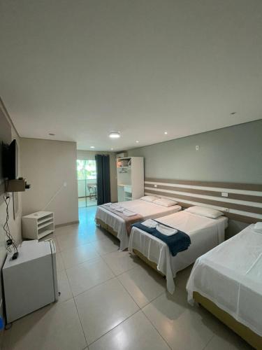 a bedroom with two beds and a television in it at Pousada Recanto Armação in Penha