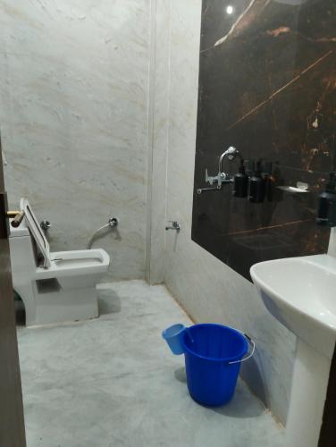a bathroom with a toilet and a sink and a bucket at Nanda devi hotel in Mussoorie
