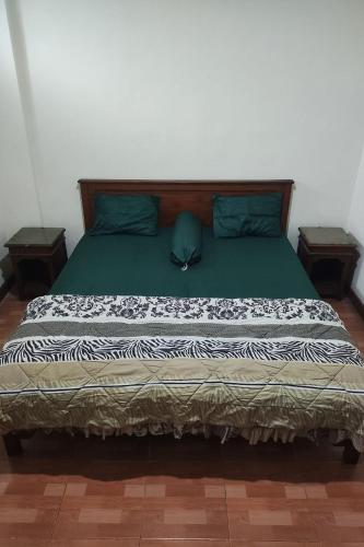 ein Schlafzimmer mit einem Bett mit grünen Laken und blauen Kissen in der Unterkunft Hotel Bima in Klaten