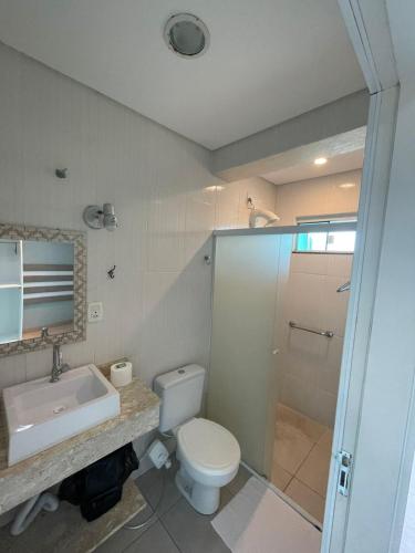 a bathroom with a toilet and a sink and a shower at Pousada Recanto Armação in Penha