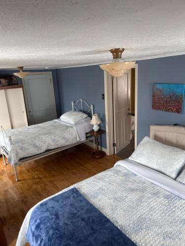 a bedroom with two beds and a blue wall at Chez Odette, suite international in Roberval