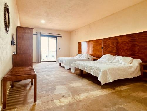 a bedroom with two beds and a large window at Hotel Suites Piamonte in Bernal