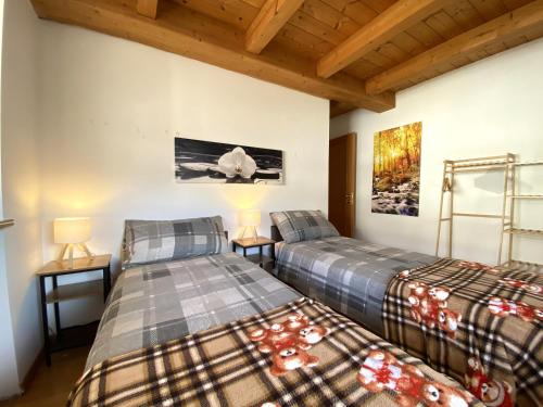 two beds in a room with wooden ceilings at My Sweet Home In The Dolomites - Casa LaLu in Cavalese
