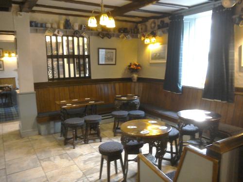 a dining room with tables and stools in a restaurant at The Foresters Arms in Grassington