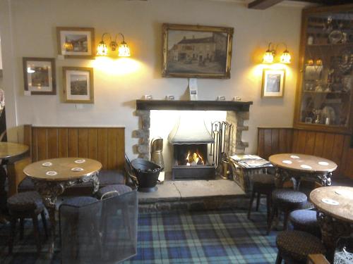 a fireplace in a restaurant with tables and a fire place at The Foresters Arms in Grassington