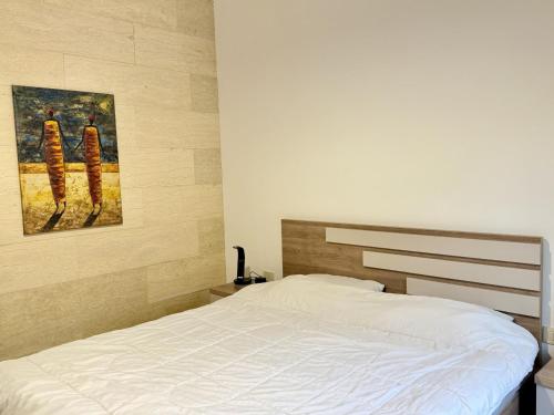 a bedroom with a bed and a painting on the wall at Les Voiles Kfar Aabida in Fad‘ūs