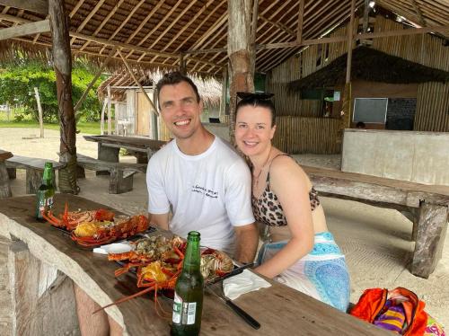 a man and a woman standing next to a table with food at Port Olry BBQ Table and Camping Side in Port-Olry