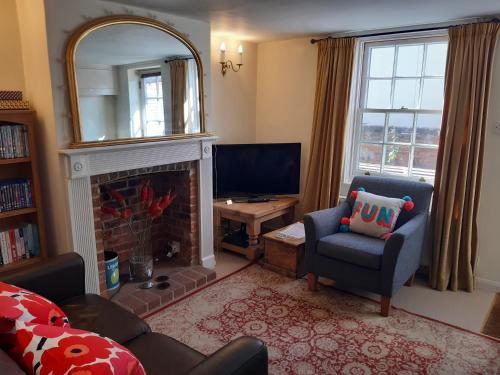 a living room with a fireplace and a mirror at Loom Cottage in Southwold