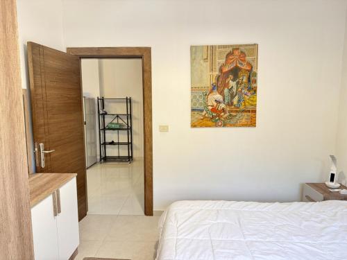 a bedroom with a bed and a painting on the wall at Les Palmiers Kfar Aabida in Fad‘ūs