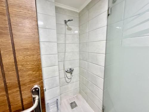 a bathroom with a shower with white tiles at Les Palmiers Kfar Aabida in Fad‘ūs