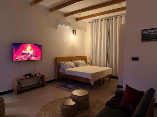 a bedroom with a bed and a tv on the wall at Kilistone Apartments in Uru