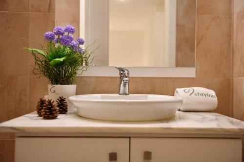 a bathroom with a sink and a mirror and flowers at Aspen - Duplex 1-BR in Faraya in Fārayyā