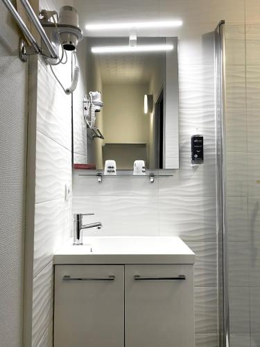 a bathroom with a sink and a mirror at Brit Hotel Le Surcouf in Saint Malo