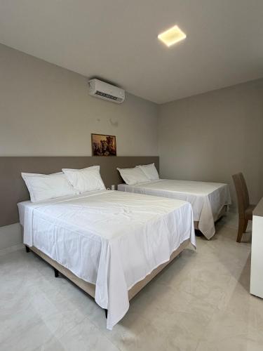 a bedroom with two beds with white sheets at Loft Brisas do Caeté in Bragança