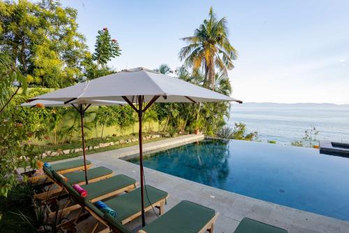 a pool with chairs and an umbrella next to the ocean at Casa Tara Villa Oceanfront Oasis Private Beach in Cruz de Huanacaxtle