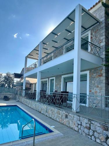 a house with a balcony and a swimming pool at Villa Korina in Nea Epidavros