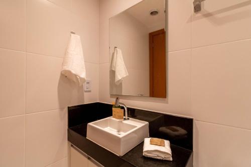 a white bathroom with a sink and a mirror at Prime Stay 2102 in Guarulhos