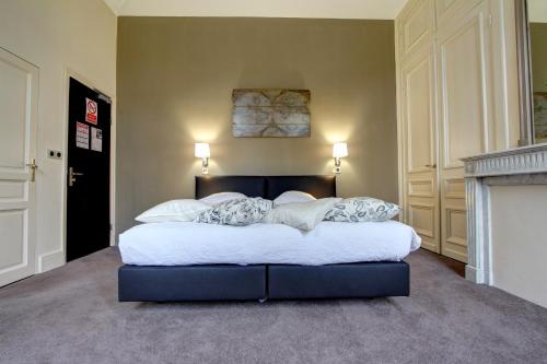 a bedroom with a large bed with white sheets at Logis Manoir de Fourcy in Corbehem