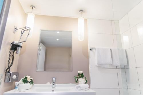 a white bathroom with a sink and a mirror at Mercure Angers Centre de Congrès in Angers