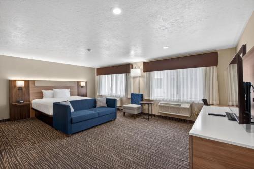 a hotel room with a bed and a blue couch at Best Western Timpanogos Inn in Lehi