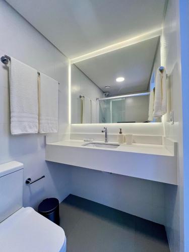 a white bathroom with a sink and a toilet at Casa Veleiro in Florianópolis