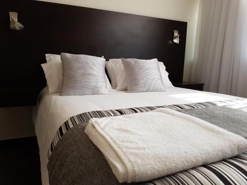 een slaapkamer met een bed met witte lakens en kussens bij Tempora Apart Hotel in Antofagasta