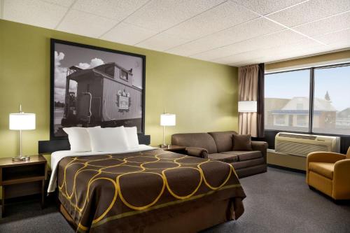 a hotel room with a bed and a couch at Super 8 by Wyndham Hearst ON in Hearst