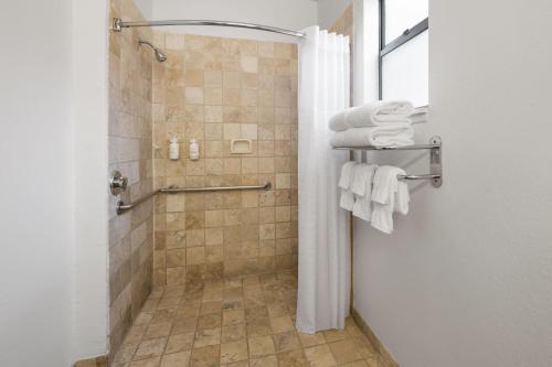 a bathroom with a shower with white towels at Ramada Suites by Wyndham San Diego Hotel Circle Area in San Diego