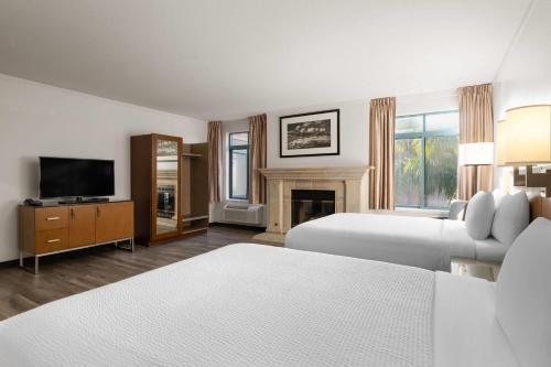 a hotel room with two beds and a fireplace at Ramada Suites by Wyndham San Diego Hotel Circle Area in San Diego