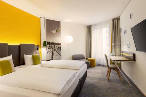 a hotel room with two beds and a desk at Sunday Hotel Leipzig in Leipzig