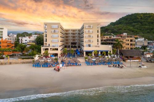 an aerial view of a beach with chairs and buildings at Decameron La Marina Guayabitos, Ramada All-Inclusive Resort in Rincon de Guayabitos