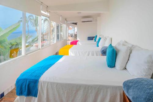 a room with three beds with a view of the ocean at Ocean Front Villa - Private Pool and Ocean Access in Puerto Vallarta