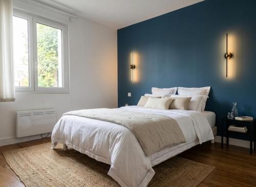 a bedroom with a large bed with a blue wall at Maison plain pied hyper centre avec véranda 5 min à pied plage Royan 3 chambres in Royan