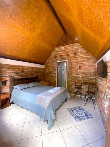 a bedroom with a bed and a brick wall at Chalé Ametista in Ouro Preto