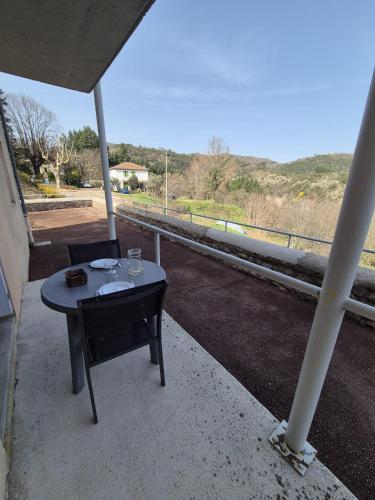 a table and chair on a porch with a view of a road at Gîte La Vallée RDC Neyrac-les-Bains in Meyras