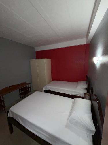 two beds in a small room with a red wall at Apartment in Corinth in Corinthe