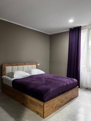 a bedroom with a wooden bed with a purple blanket at Rachnari Guest House in Gari